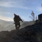 A man walking uphill with an axe on a landscape of chopped trees