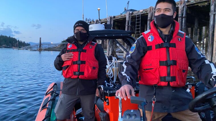 Two Coastal Nations Coast Guard Auxiliary members with life jackets on a boat.