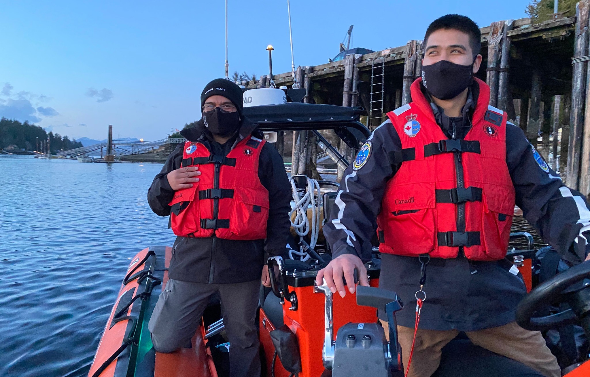 Two Coastal Nations Coast Guard Auxiliary members with life jackets on a boat.