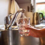 tap water and a person holding a glass under the faucet