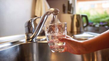 tap water and a person holding a glass under the faucet